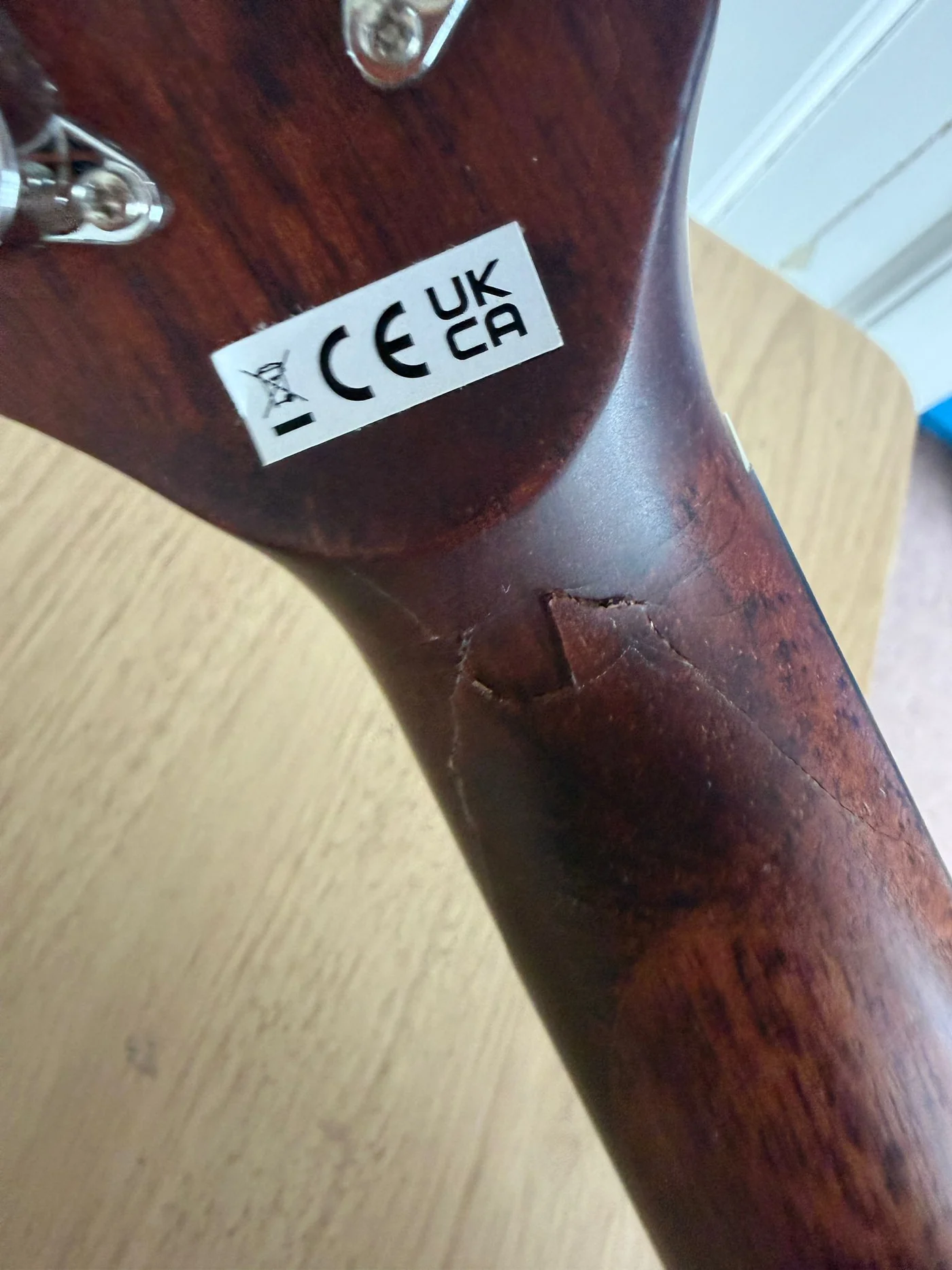 Broken guitar neck before repair with a visible crack at the headstock