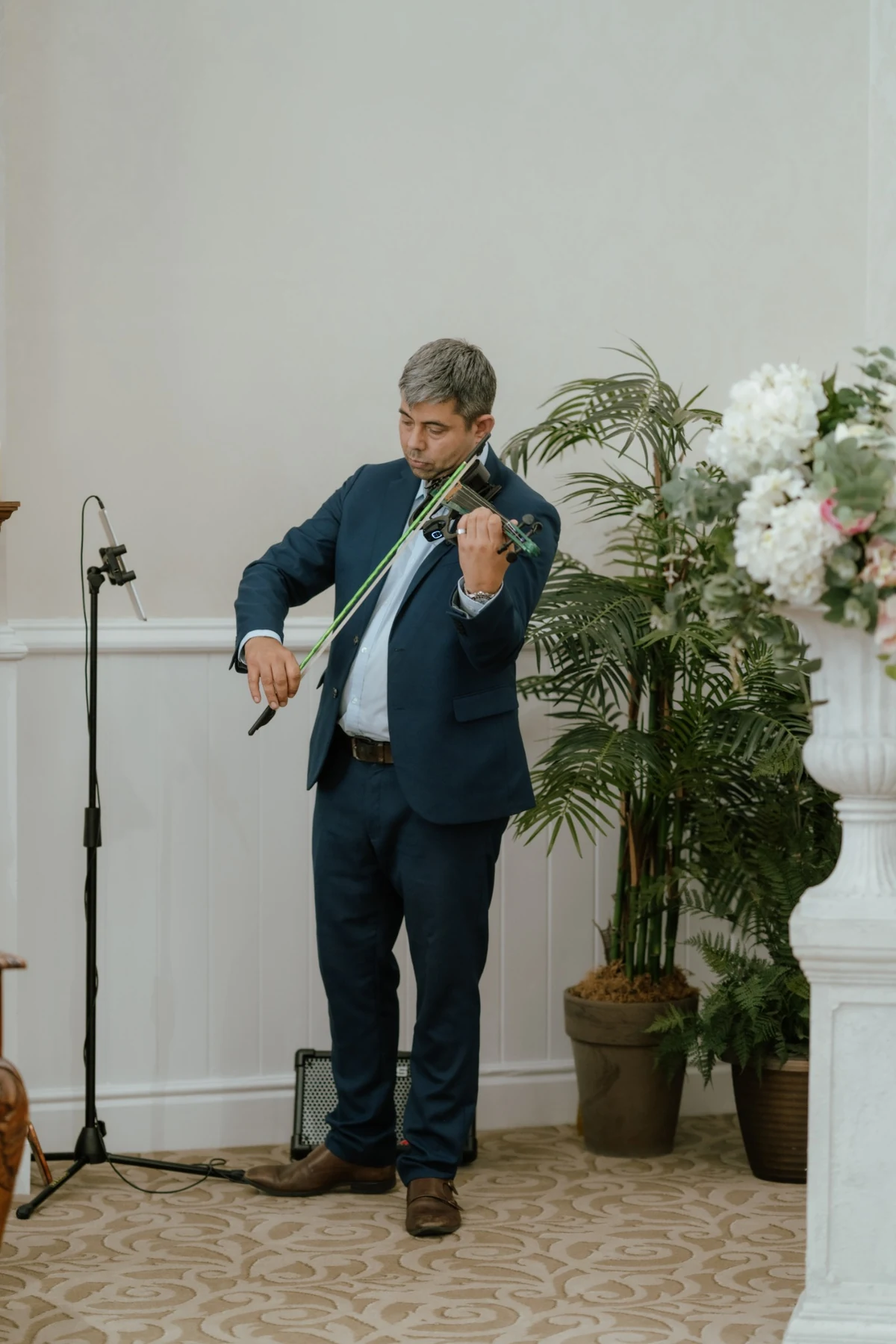 James Taylor performing electric violin beside floral wedding decor
